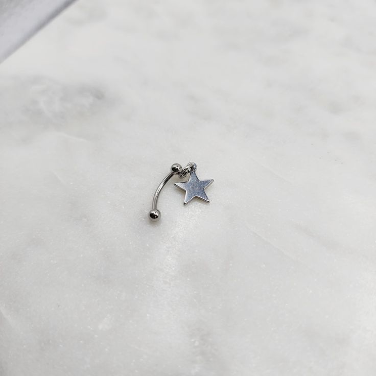 a star shaped nose piercing on top of a white marble counter with a silver ball in the middle