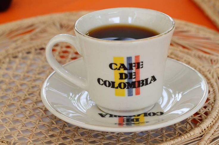 a cup of coffee sitting on top of a saucer next to an orange tablecloth