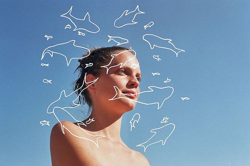 a woman standing in front of the ocean with white lines drawn all over her face