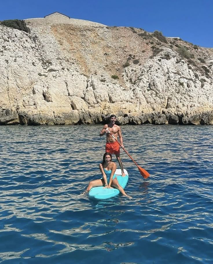 two people are paddling on surfboards in the water