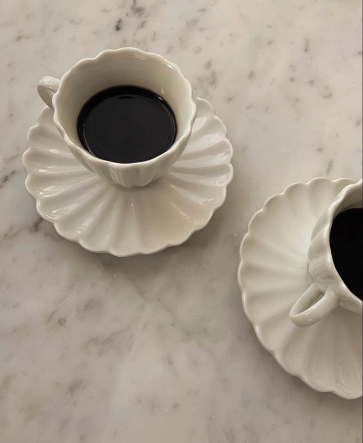 two cups of coffee sitting on top of a marble table