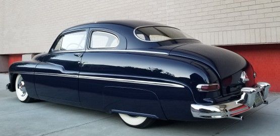 an old blue car parked in front of a building