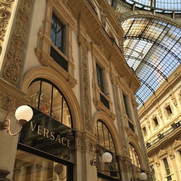 the inside of a building with many windows and lights on it's sides, in front of a glass ceiling