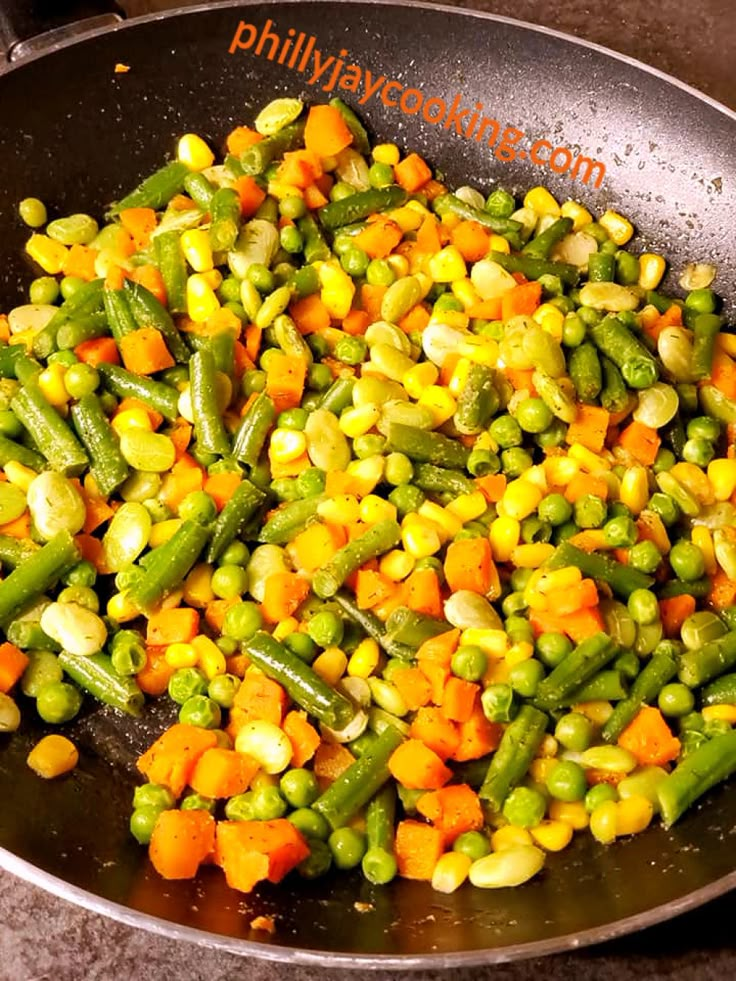 peas, carrots and corn cooking in a wok on the stove top for dinner