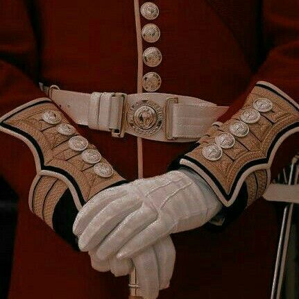 a close up of a person wearing white gloves and holding a cane in their hands