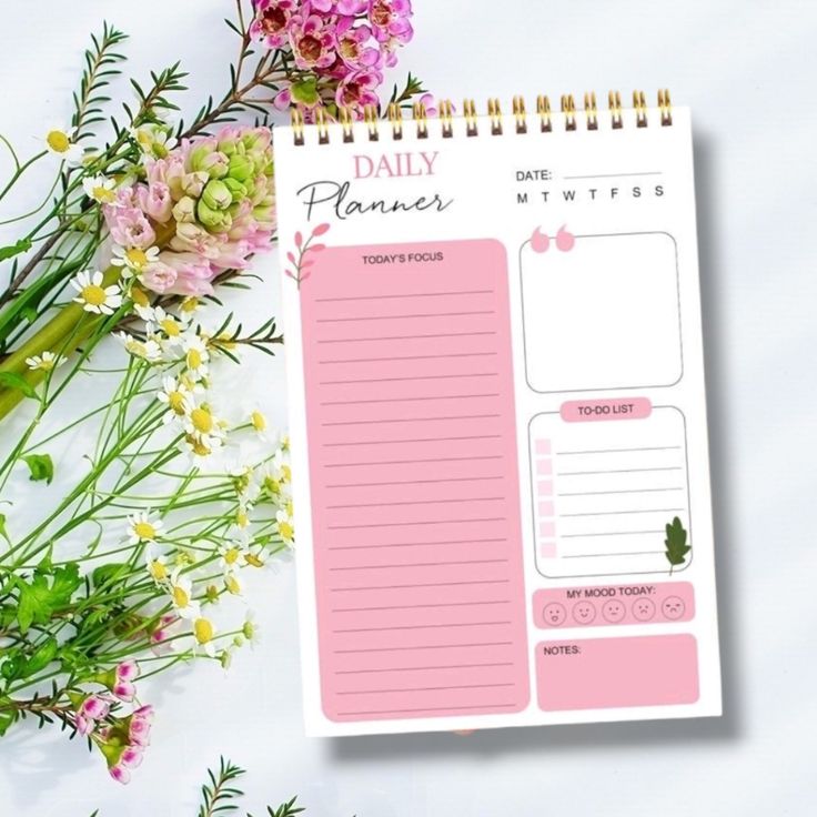 the daily planner is next to some flowers