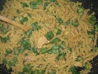 rice and vegetables being cooked in a wok with a wooden spoon on the side