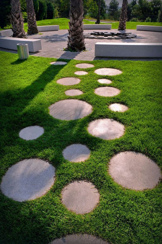 stepping stones are arranged in the grass near palm trees and an outdoor seating area for people to sit on