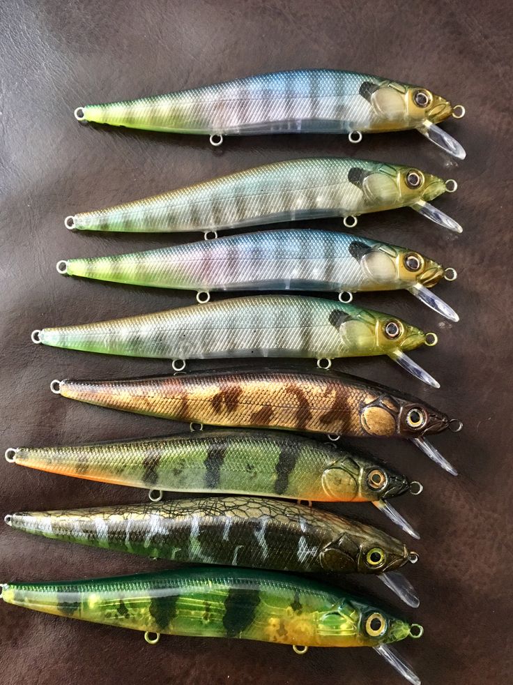 five different types of fishing lures lined up in a row on a brown surface