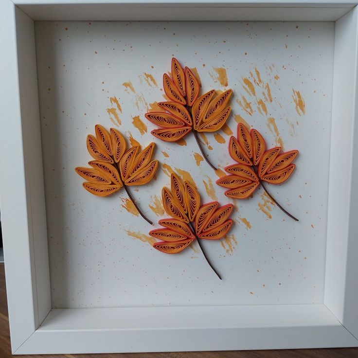 three orange leaves are in a white frame