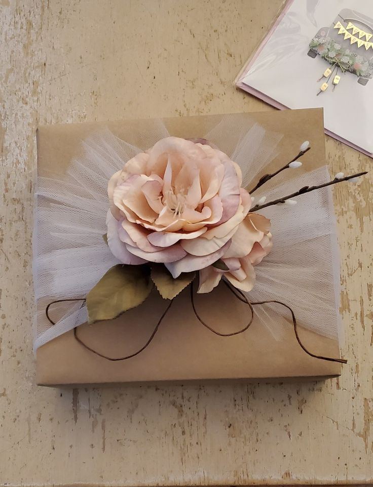 a gift wrapped in brown paper with a pink flower on it and some other items