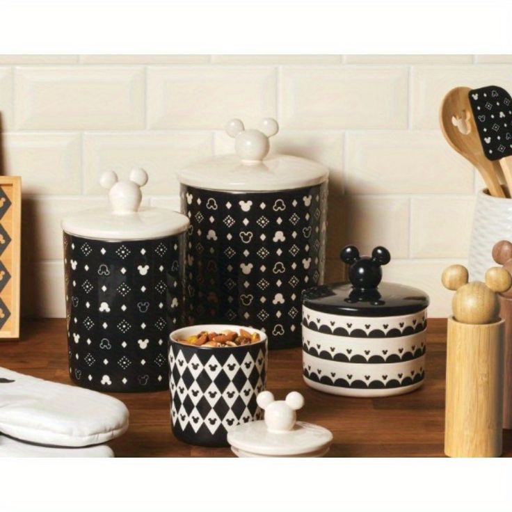 black and white kitchen canisters with mickey mouse designs on them, along with utensils