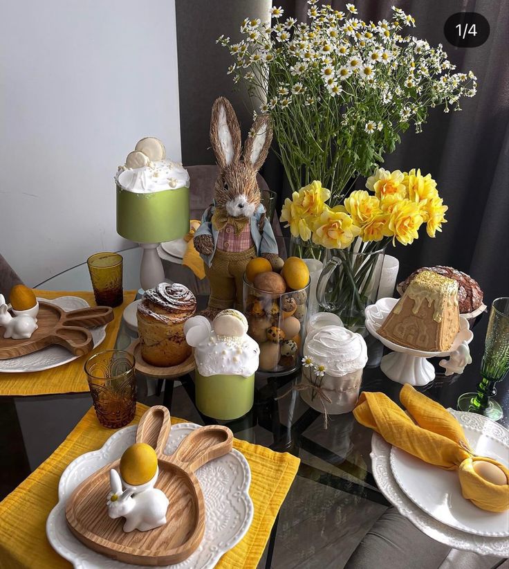 a table topped with plates covered in cake and flowers next to a vase filled with yellow flowers