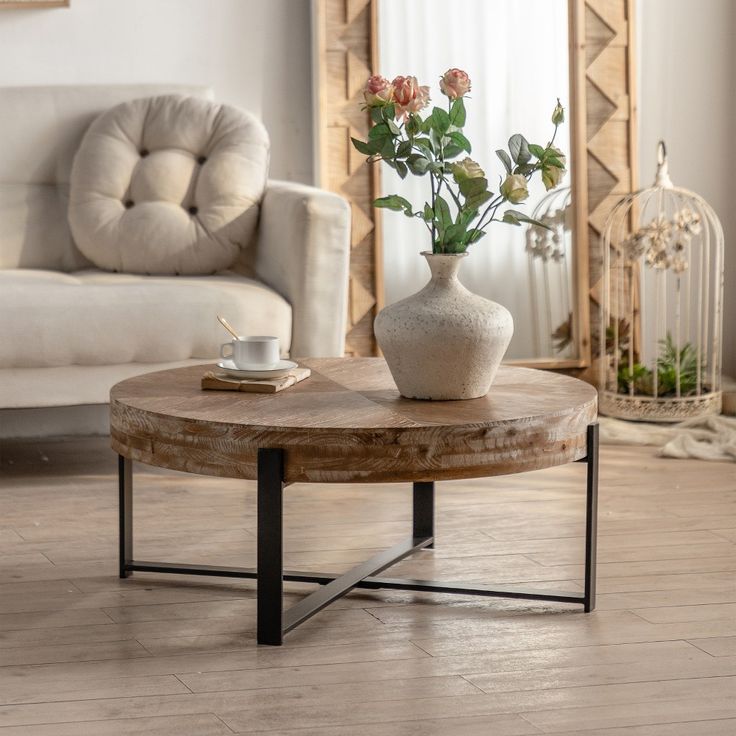 a coffee table with flowers in a vase on it and a birdcage next to it