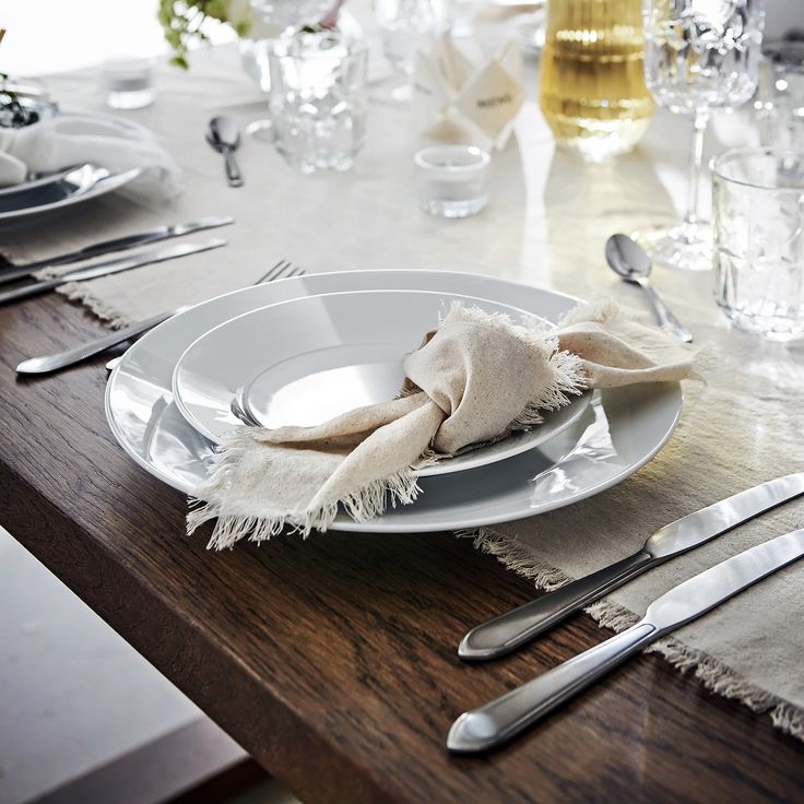 a table set with plates, silverware and napkins