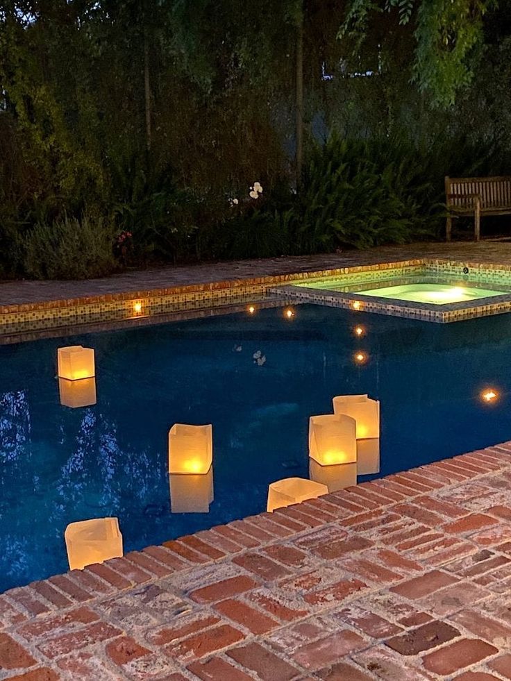 lighted paper lanterns sitting on the edge of a swimming pool