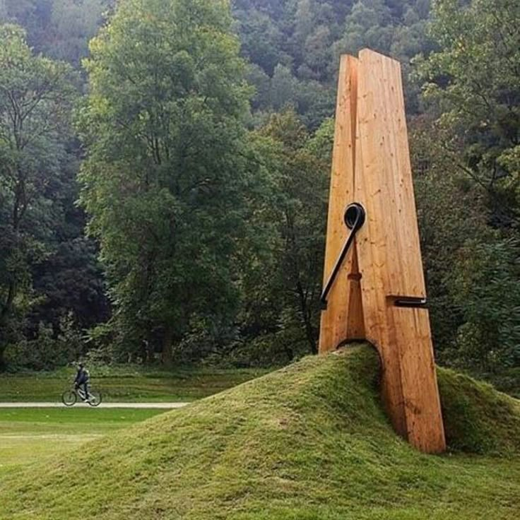 a large wooden object sitting on top of a lush green field