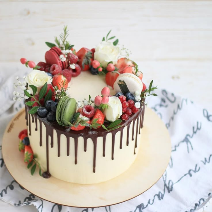 a cake decorated with fresh fruit and chocolate drizzle