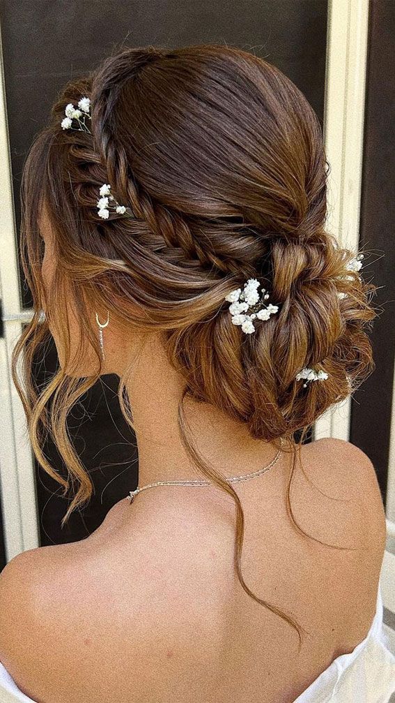 the back of a woman's head with flowers in her hair, wearing a white dress