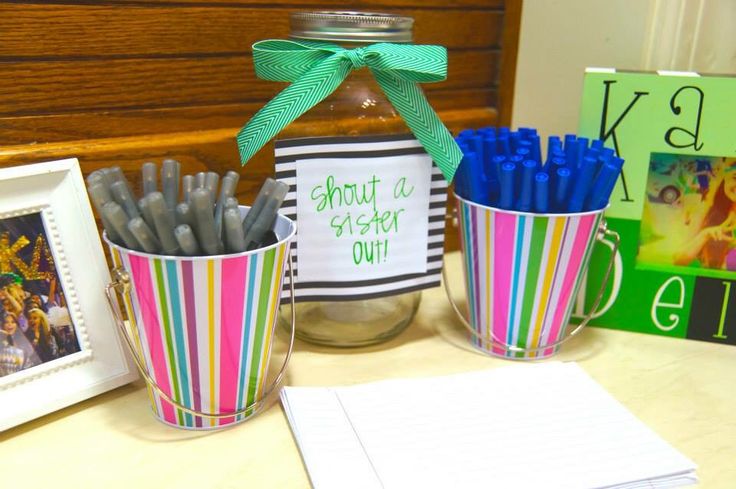 two mugs filled with pencils sitting on top of a desk next to a framed photo