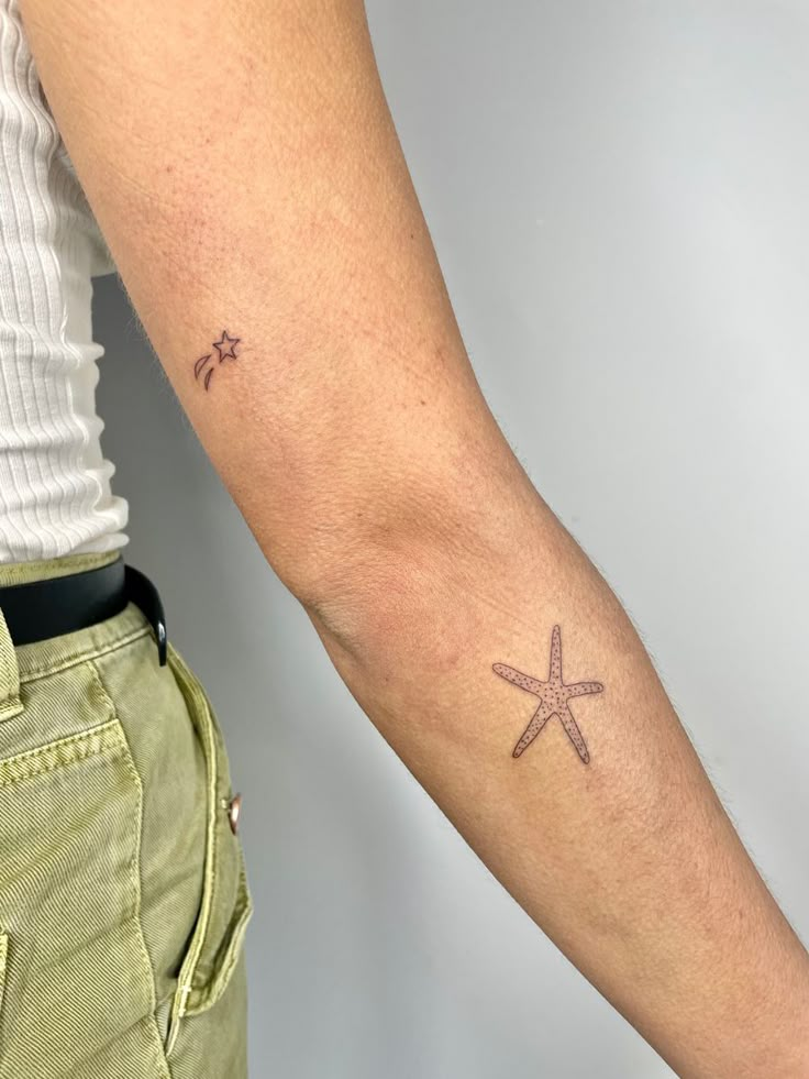 a person with a small starfish tattoo on their left arm and the other arm