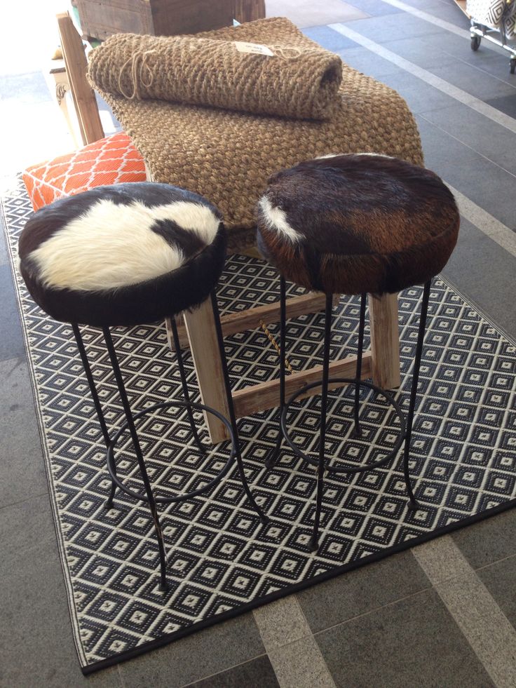 two stools sitting on top of a black and white rug next to each other