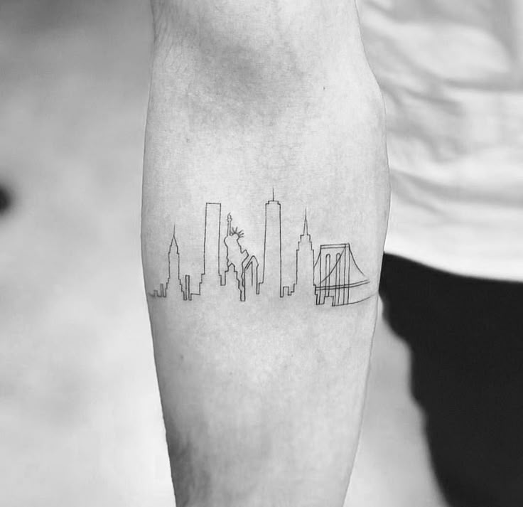 a black and white photo of a person's arm with a city skyline tattoo on it