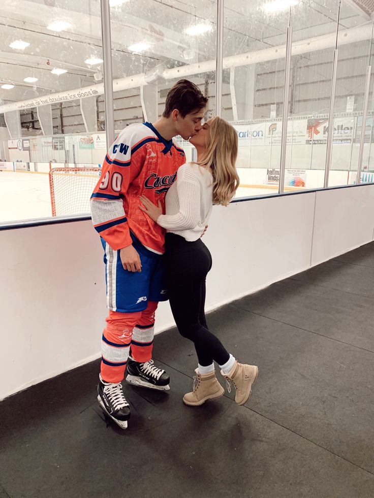 a man and woman are kissing in front of an ice hockey goalie's rink