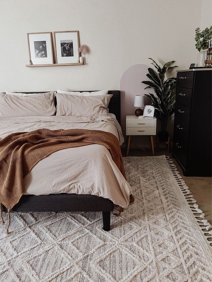 a bed sitting in a bedroom next to a dresser and two pictures on the wall