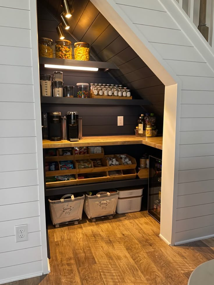 an open pantry under the stairs in a house with wood flooring and white walls