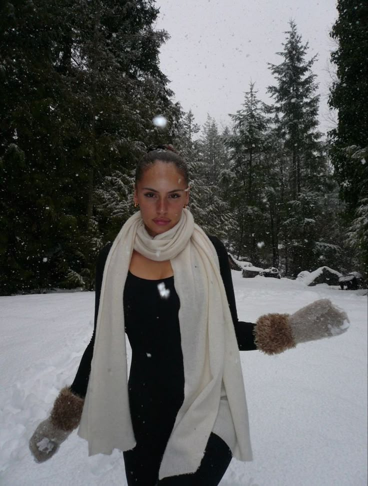 a woman is standing in the snow with her arms wrapped around her neck and wearing gloves