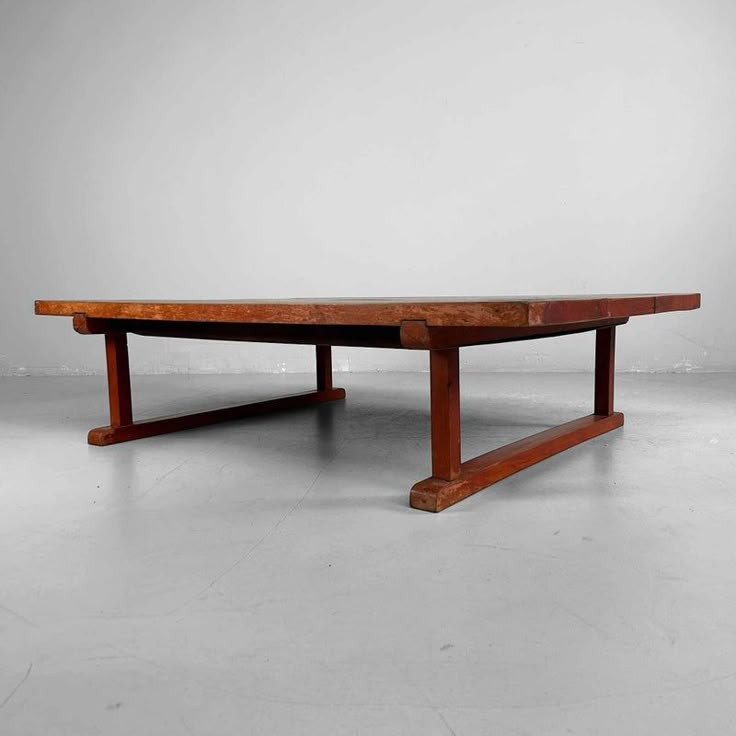 a large wooden table sitting on top of a white floor next to a gray wall