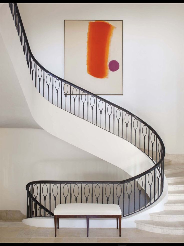 a painting on the wall next to a stair case with a bench in front of it