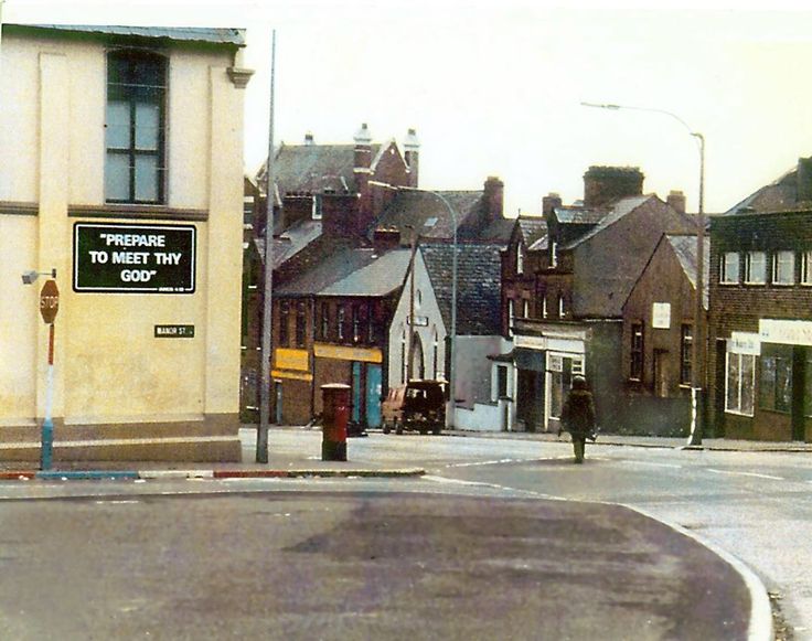 an old photo of a street corner with buildings in the background