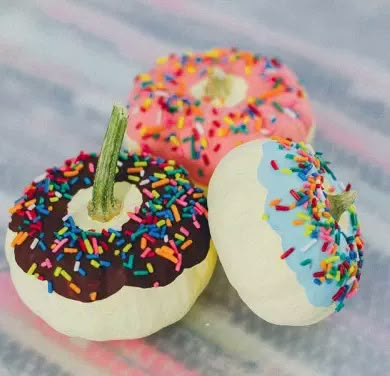 three donuts with sprinkles on them sitting on a tablecloth covered surface