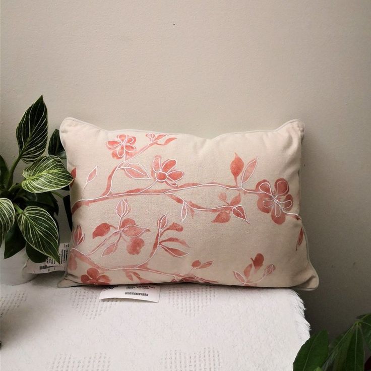 a white pillow sitting on top of a bed next to a potted plant