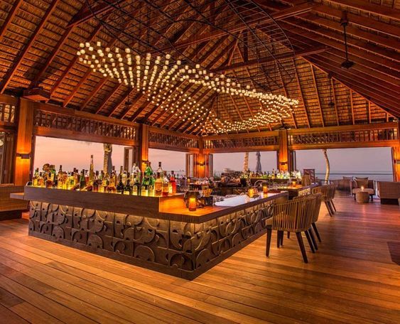 an outdoor bar with lots of bottles on the counter and lights hanging from the ceiling