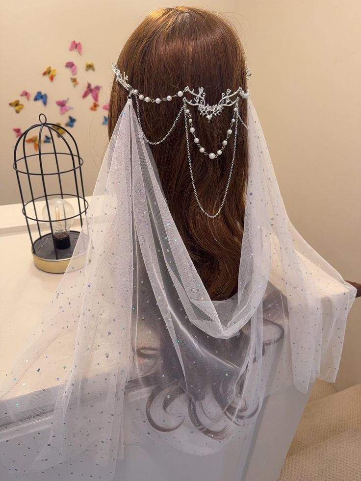 the back of a woman's head wearing a veil with pearls on it