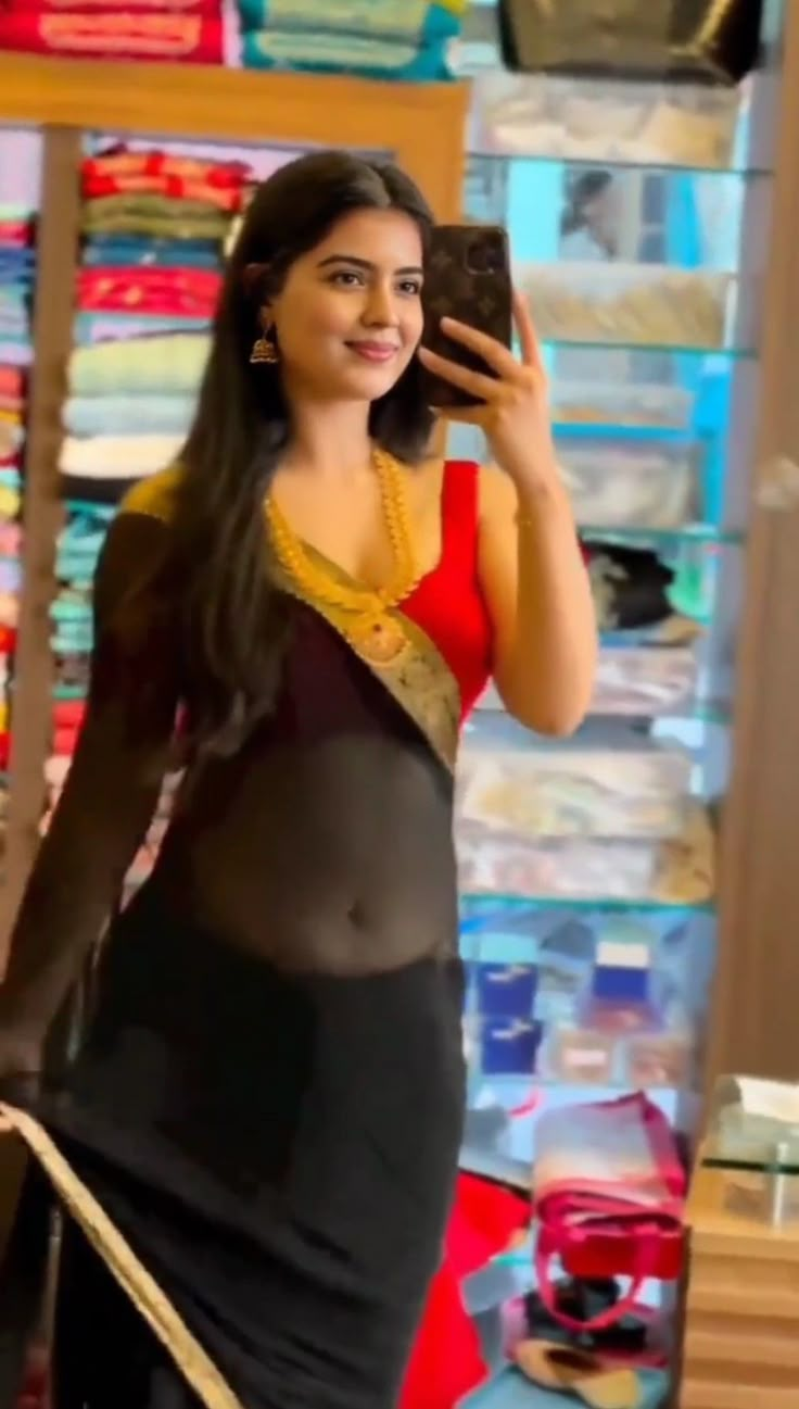 a woman in a black and red sari taking a selfie