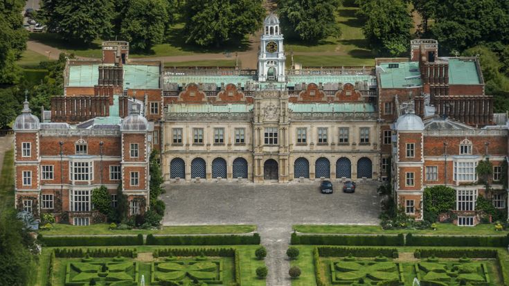 an aerial view of a large building in the middle of trees and grass, surrounded by hedges