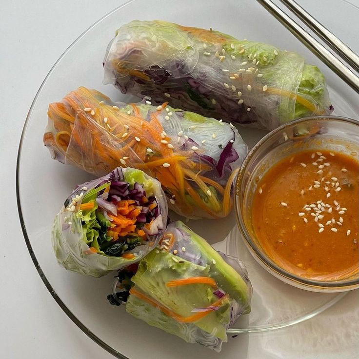 a plate topped with rolls covered in lettuce next to a bowl of dipping sauce