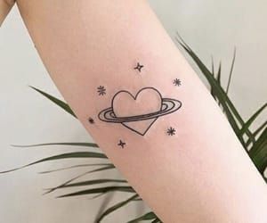 a heart tattoo on the arm with stars and saturn in the sky above it,