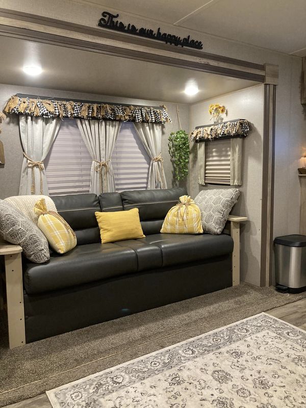 a living room with black leather couches and yellow pillows on the floor next to a rug