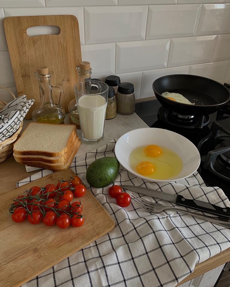 a kitchen counter with eggs, tomatoes and bread on it