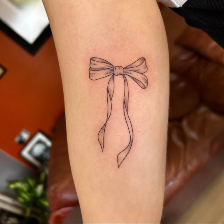 a woman's arm with a bow tattoo on the left side of her leg