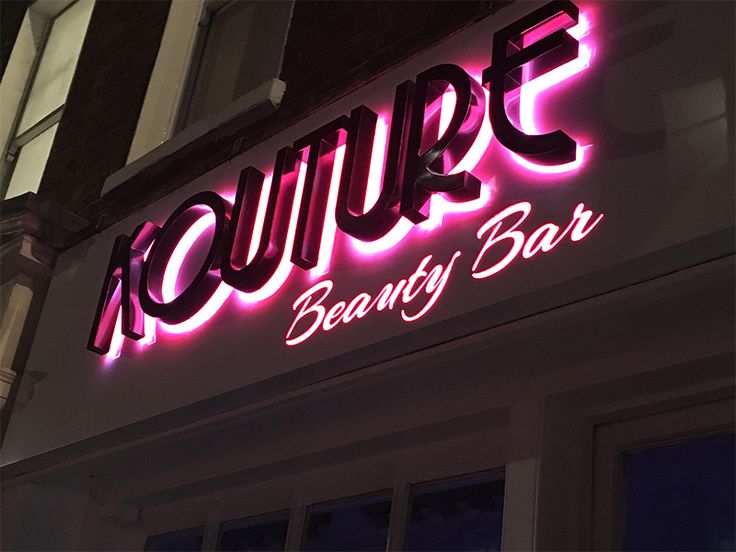 a neon sign that says kouppe beauty bar on the side of a building