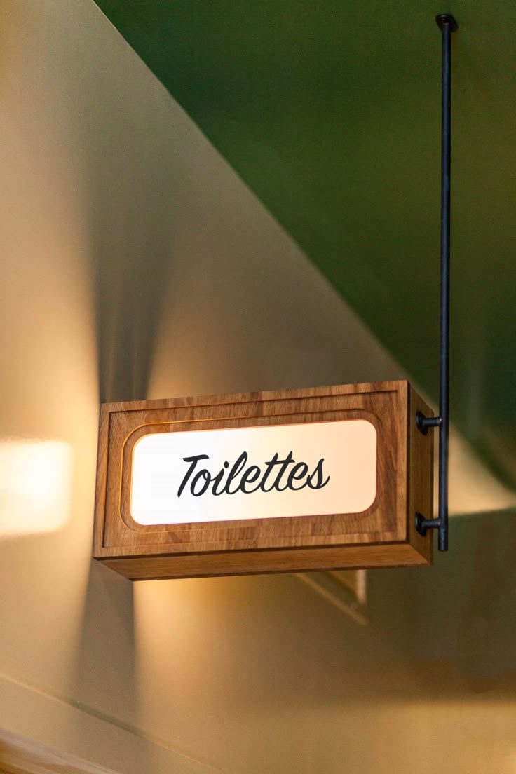 a sign hanging from the ceiling that says toilette's in black lettering