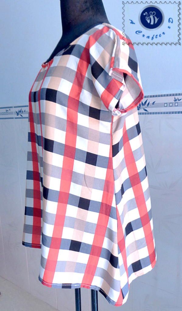 a mannequin wearing a red and white checkered shirt on a black stand