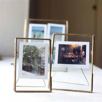 two gold frames with pictures in them sitting on a table next to each other,