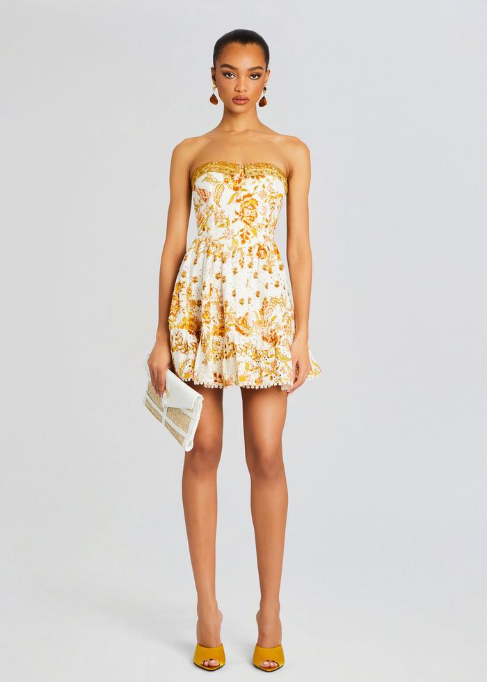 a woman wearing a yellow and white dress with an orange flower print on the front